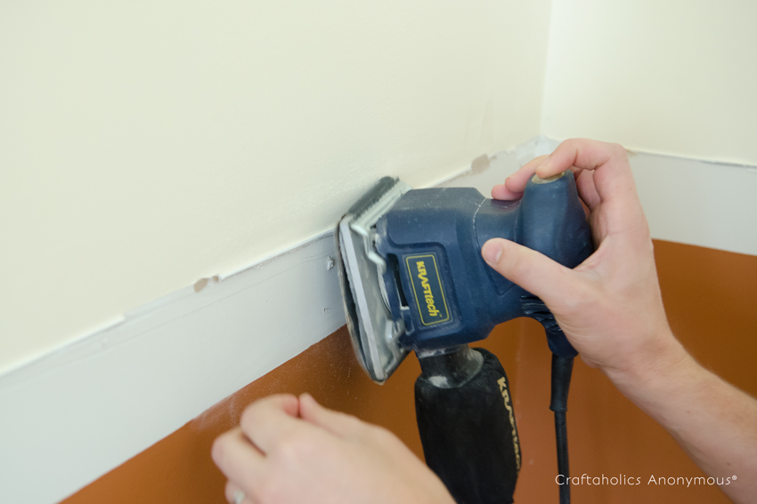 sanding a wall with a hand sander
